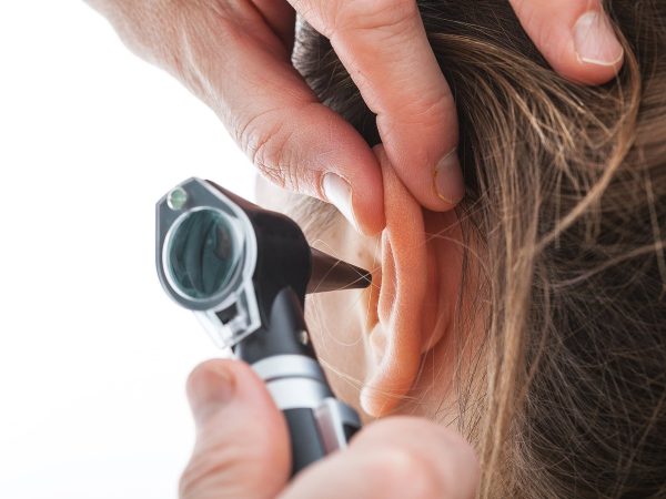 Closeup of examining ear with an otoscope